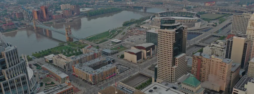 Aerial view of downtown Cincinnati with the Ohio River, a suspension bridge and a stadium.