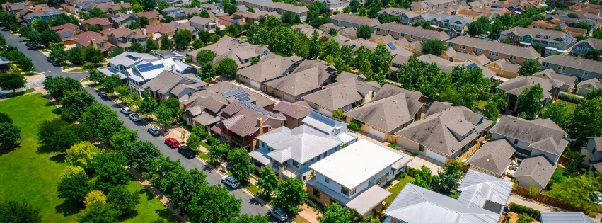 Aerial view of a dense residential neighborhood with tree-lined streets and rooftops.