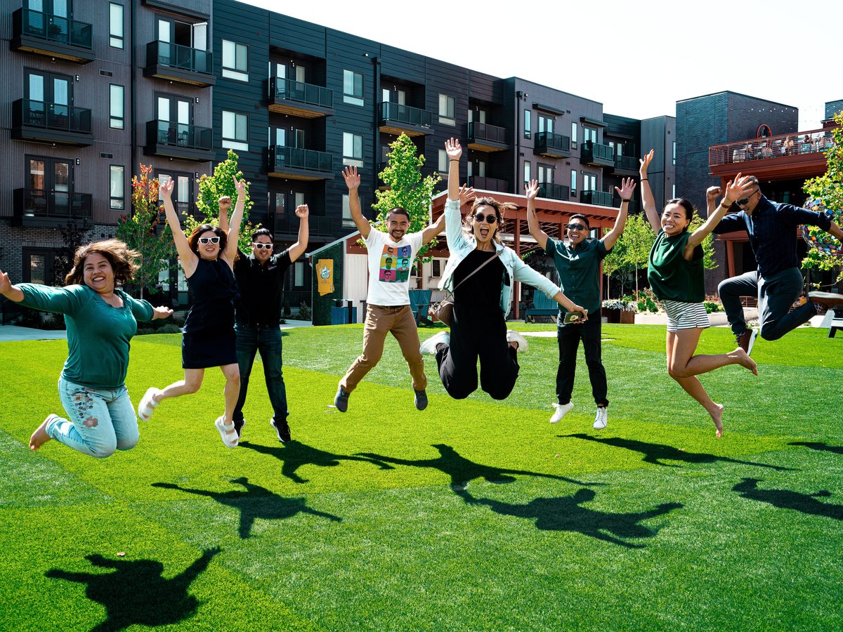 Cincinnati field trip participants jumping together outside an apartment community